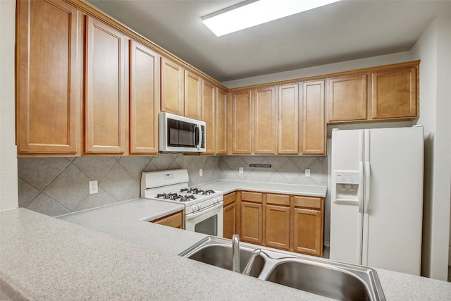 kitchen featuring white appliances, tasteful backsplash, light countertops, and a sink