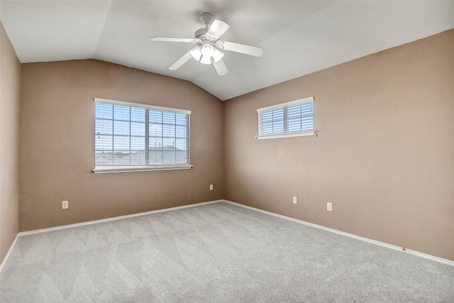 carpeted spare room featuring baseboards, vaulted ceiling, and a ceiling fan