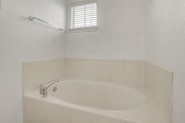 bathroom with a textured wall and a bath