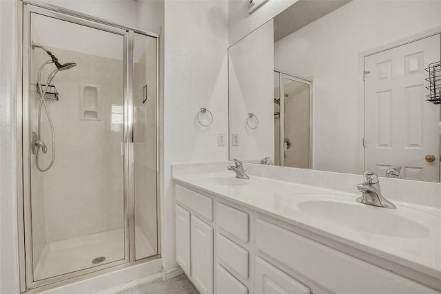 full bath with double vanity, a sink, and a shower stall