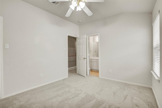 unfurnished bedroom with lofted ceiling, ensuite bath, baseboards, and light colored carpet