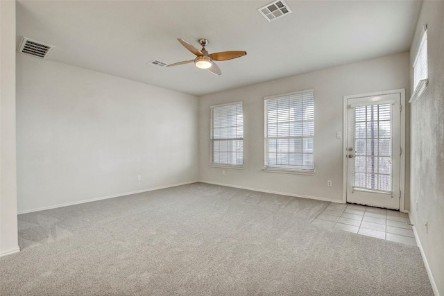 carpeted spare room featuring tile patterned flooring, visible vents, and a ceiling fan