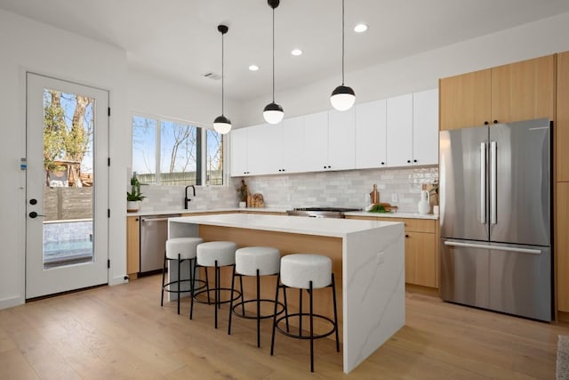 3402 Goodwin Ave Unit 1, Austin, TX 78702 - kitchen with stainless steel appliances, a kitchen island, light wood-type flooring, a breakfast bar area, and recessed lighting