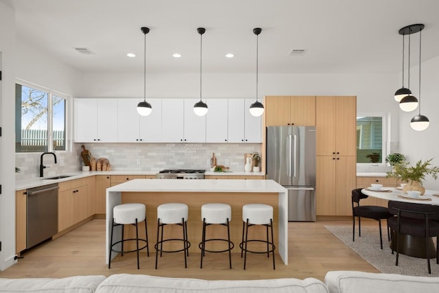 3402 Goodwin Ave Unit 1, Austin, TX 78702 - kitchen featuring appliances with stainless steel finishes, a sink, a kitchen bar, light wood-style flooring, and recessed lighting