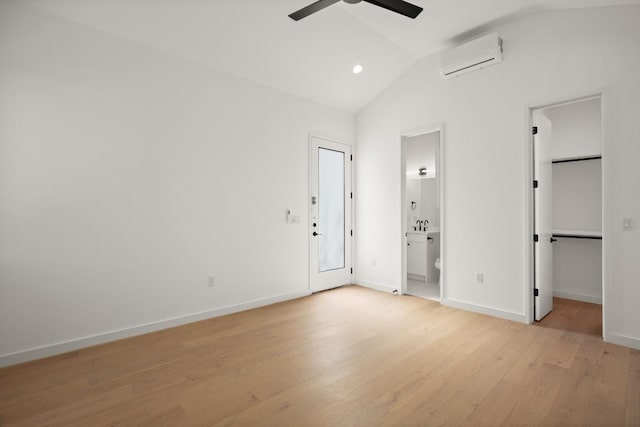 empty room with baseboards, a ceiling fan, vaulted ceiling, an AC wall unit, and light wood-style floors