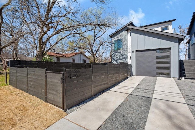 view of home's exterior featuring board and batten siding, fence, driveway, and a garage