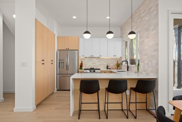 kitchen featuring a kitchen bar, a sink, range, a peninsula, and stainless steel fridge with ice dispenser