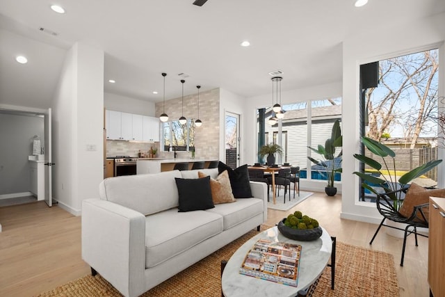 living area with light wood-style floors, visible vents, baseboards, and recessed lighting