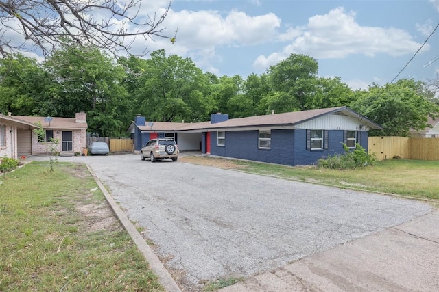 single story home featuring driveway, a chimney, fence, a front yard, and brick siding