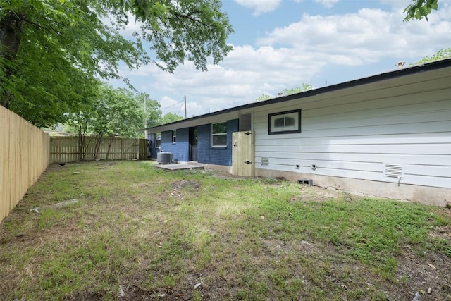 back of property featuring crawl space, a fenced backyard, a lawn, and central AC