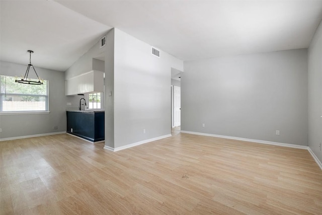 unfurnished living room with visible vents, a sink, and light wood finished floors