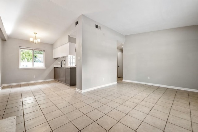 spare room with lofted ceiling, visible vents, a notable chandelier, and a sink