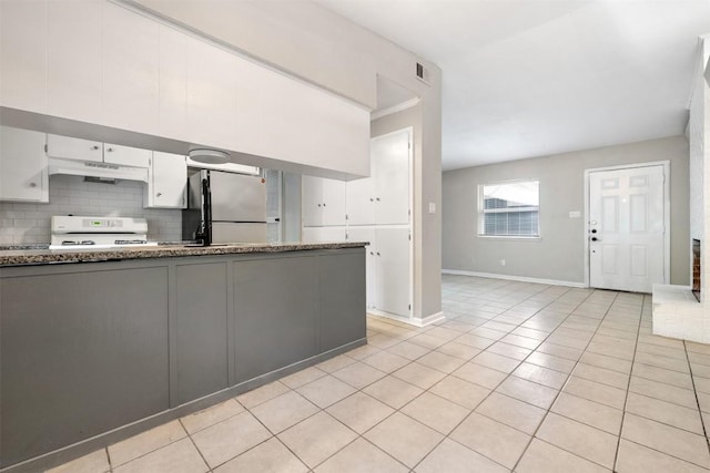 kitchen with under cabinet range hood, white range, white cabinets, freestanding refrigerator, and tasteful backsplash