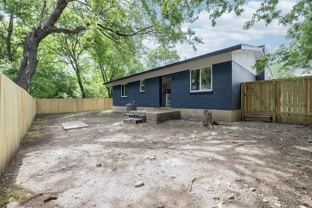 back of property with cooling unit, a fenced backyard, and brick siding