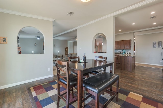 dining area with baseboards, visible vents, dark wood-type flooring, and crown molding