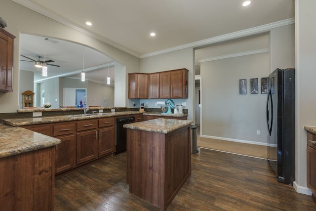 kitchen featuring dark wood-style flooring, a ceiling fan, ornamental molding, a kitchen island, and black appliances