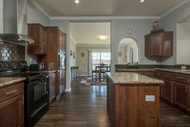 kitchen with black electric range oven, ornamental molding, a center island, wall chimney exhaust hood, and stainless steel microwave