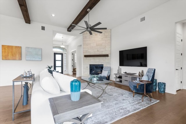 living area featuring beam ceiling, wood finished floors, and visible vents