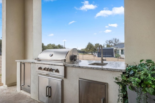 view of patio with exterior kitchen, area for grilling, fence, and a sink