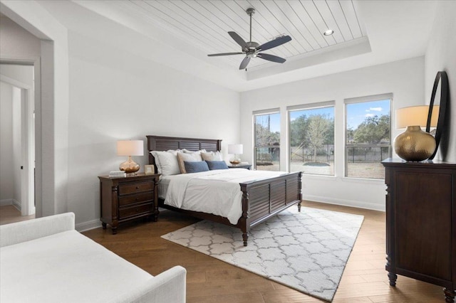 bedroom featuring baseboards, a raised ceiling, wooden ceiling, ceiling fan, and wood finished floors