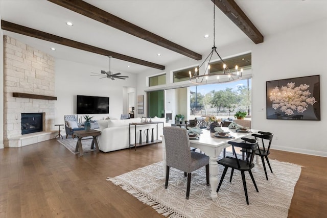 dining area featuring a fireplace, wood finished floors, beamed ceiling, baseboards, and ceiling fan with notable chandelier