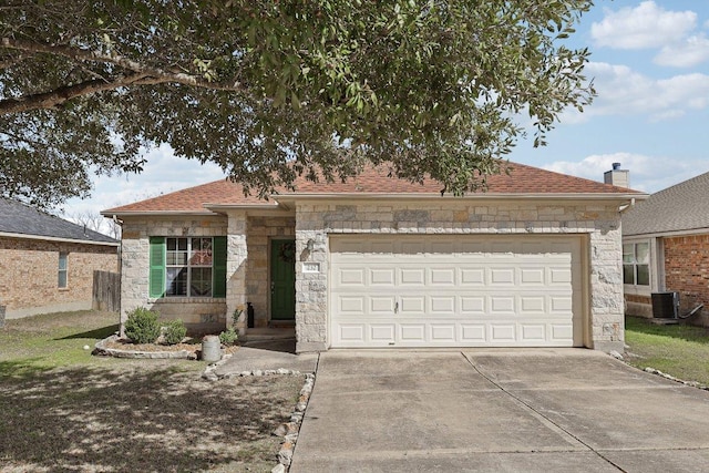 view of front facade with driveway, a shingled roof, central AC unit, stone siding, and an attached garage