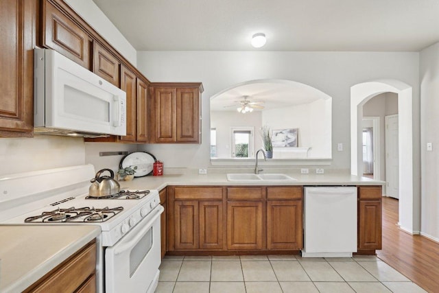 kitchen featuring white appliances, brown cabinets, a sink, and light countertops