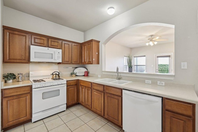 kitchen with white appliances, brown cabinets, a sink, and light countertops