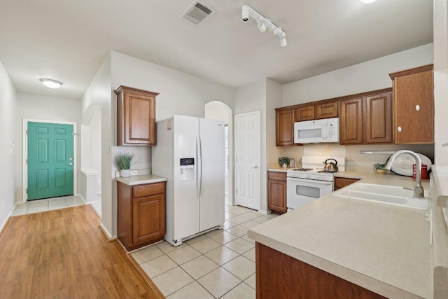 kitchen with arched walkways, light countertops, visible vents, a sink, and white appliances