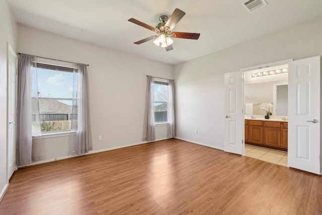 unfurnished bedroom with light wood-type flooring, baseboards, visible vents, and ensuite bathroom