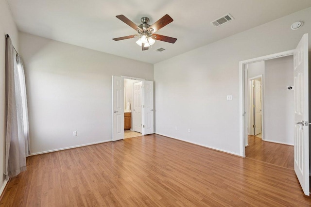 unfurnished bedroom with ensuite bathroom, visible vents, and light wood-style floors