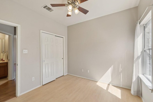 unfurnished bedroom featuring light wood-type flooring, baseboards, visible vents, and a closet