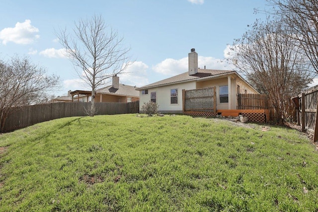 rear view of property with a lawn, a chimney, a fenced backyard, and stucco siding