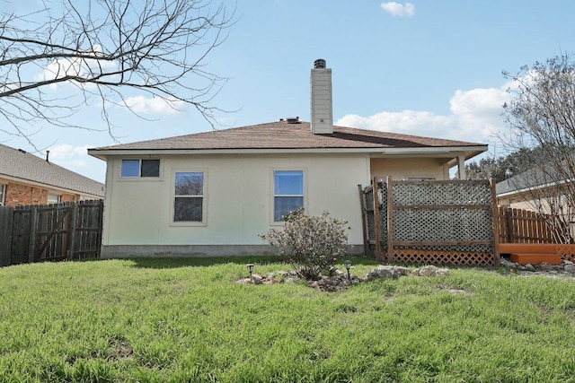 back of house with a chimney, fence, a deck, and a lawn