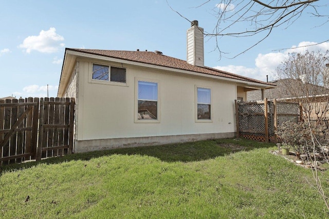 rear view of property featuring a yard, a chimney, and fence