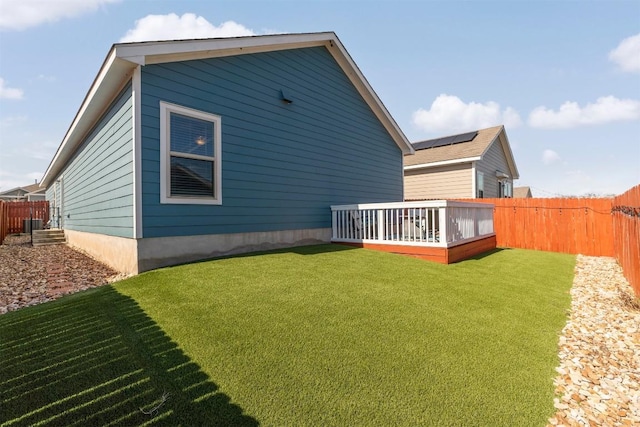 rear view of house with a deck, a lawn, and a fenced backyard