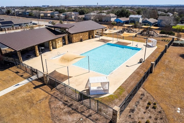 community pool featuring a patio area, a residential view, fence, and an exterior structure