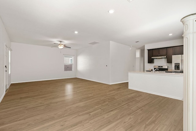 7016 Spirit Hill Rd, Austin, TX 78744 - unfurnished living room with light wood-style flooring, a ceiling fan, baseboards, recessed lighting, and a sink