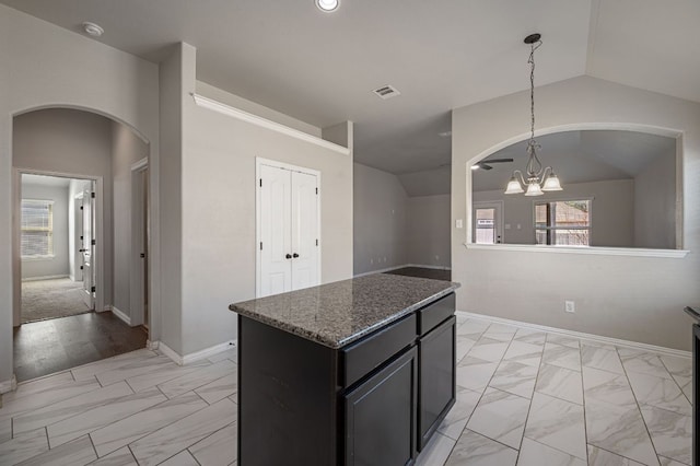 kitchen with vaulted ceiling, marble finish floor, dark cabinetry, an inviting chandelier, and pendant lighting