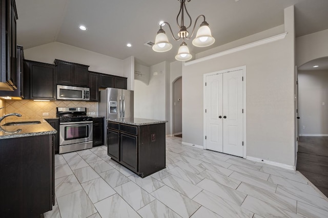 kitchen featuring arched walkways, visible vents, appliances with stainless steel finishes, a sink, and a kitchen island