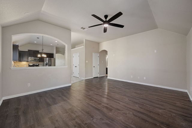 unfurnished living room featuring baseboards, visible vents, dark wood-style floors, vaulted ceiling, and ceiling fan with notable chandelier