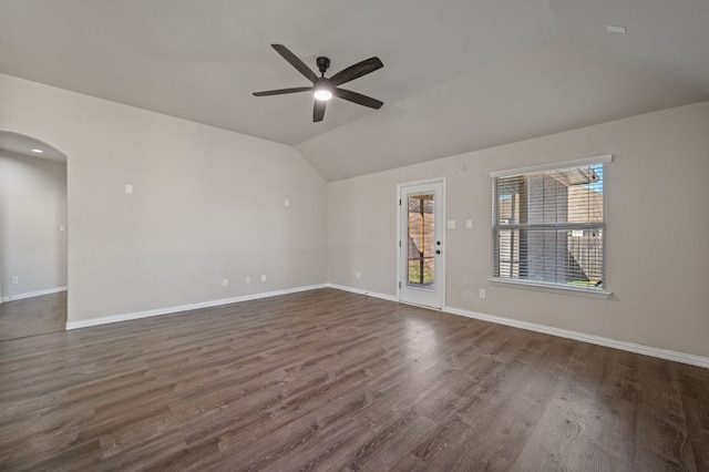 unfurnished room with lofted ceiling, baseboards, arched walkways, and dark wood-style flooring