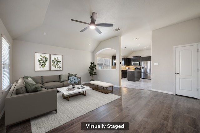 living room featuring lofted ceiling, visible vents, plenty of natural light, and wood finished floors