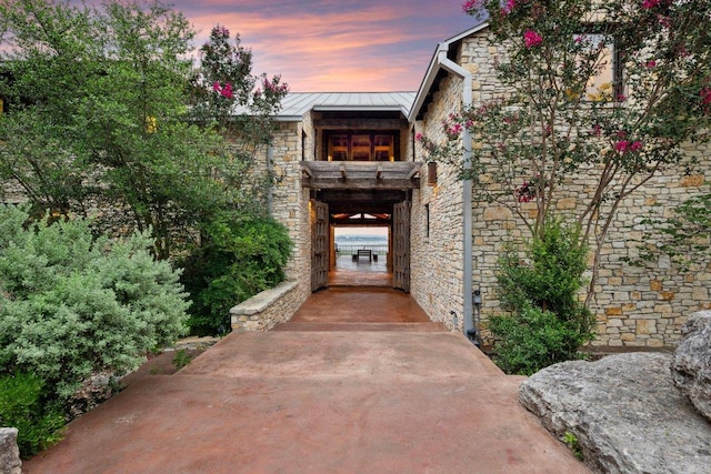 view of exterior entry with stone siding, metal roof, and a standing seam roof