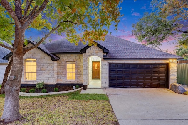 view of front facade featuring a garage, concrete driveway, a shingled roof, and a front yard