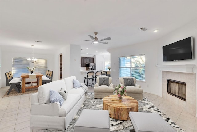 2916 Chisholm Trl, Austin, TX 78734 - living room with light tile patterned flooring, a tile fireplace, a ceiling fan, a chandelier, and arched walkways