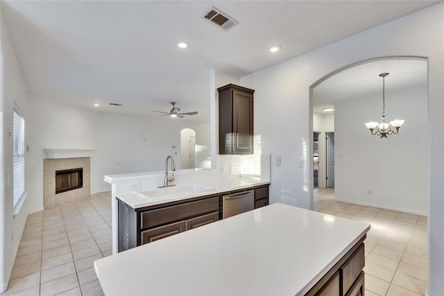 kitchen with arched walkways, a fireplace, a sink, visible vents, and dishwasher