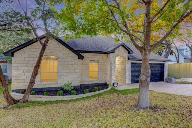 view of front of property with central air condition unit, a garage, concrete driveway, roof with shingles, and a front yard