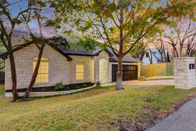 single story home featuring an attached garage, fence, driveway, roof with shingles, and a front lawn