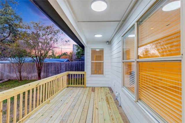 deck at dusk featuring fence